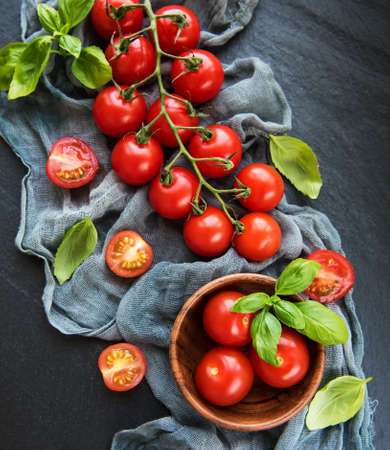Cherry tomatoes and green basil on a black backgroundの写真素材