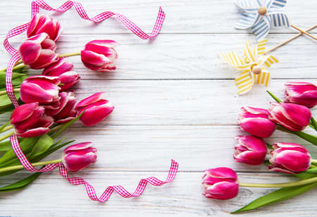 Pink spring tulips and ribbon on an old wooden backgroundの写真素材