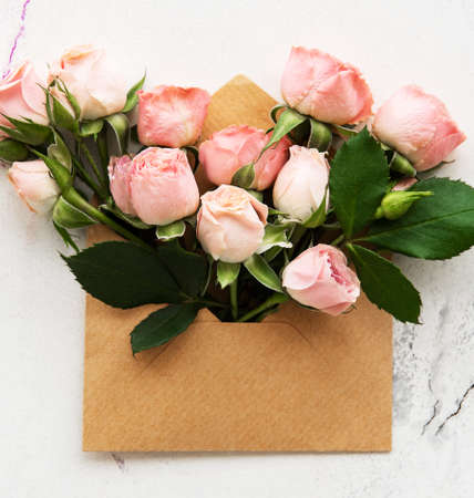 Envelope and pink roses on a white marble backgroundの写真素材