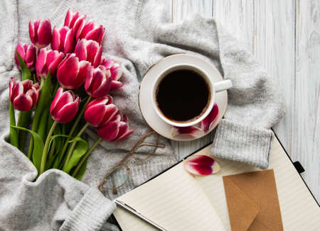Cup of coffee and pink tulips on a old wooden tableの写真素材