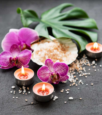 Natural spa ingredients with orchid flowers on a black concrete background