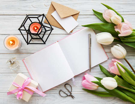 Workspace with notebook and pink tulips on a old wooden tableの写真素材