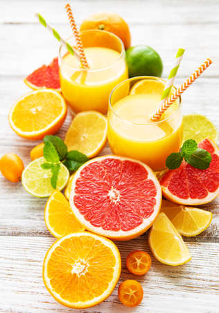Glasses of juice and citrus fruits on a wooden tableの写真素材