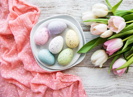 Easter eggs and tulips bouquet on a old wooden background