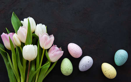 Easter eggs and tulips bouquet on a old black concrete backgroundの写真素材