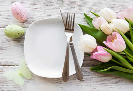 Easter eggs and tulips bouquet on a white wooden backgroundの写真素材