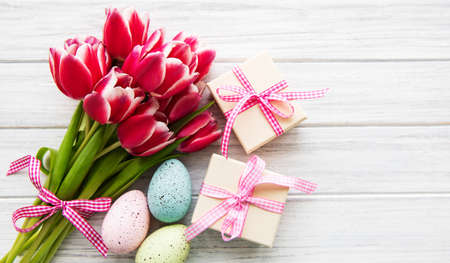 Gift boxes, easter eggs and tulips bouquet on a old wooden backgroundの写真素材