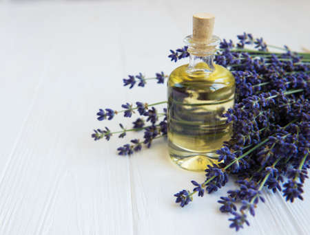 Essential oil with fresh lavender on a white wooden tableの写真素材