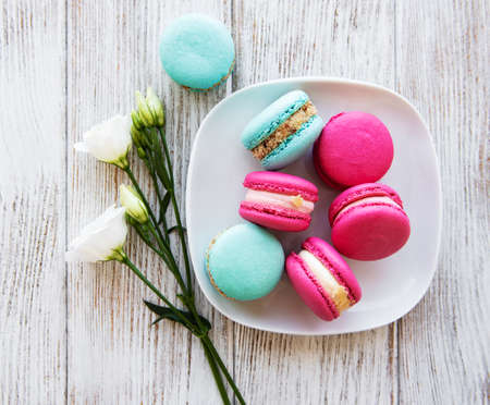 Colorful macaroons and flowers on a white wooden  backgroundの写真素材