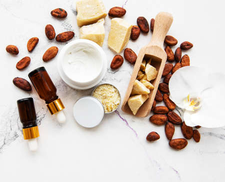 Natural spa ingredients with cocoa beans, cocoa butter and orchid flowers on a white marble backgroundの写真素材