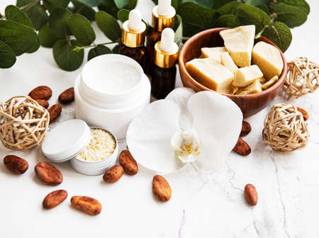 Natural spa ingredients with cocoa beans, cocoa butter and orchid flowers on a white marble backgroundの写真素材