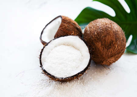 Fresh dried coconut meat chips and coconut on a white wooden tableの写真素材