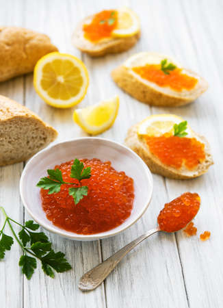 Red caviar in bowl and sandwiches on a old wooden tableの写真素材