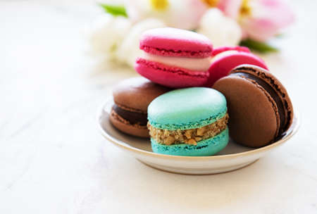 Colorful macaroons and tulips on a white marble  background