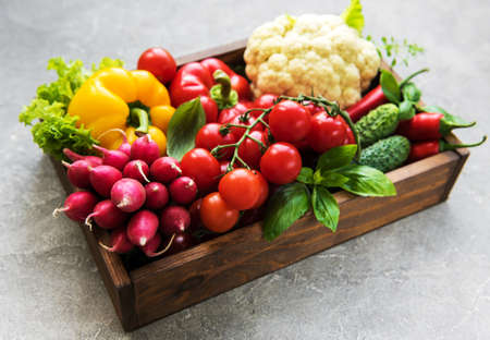Box with  different raw vegetables on a old concrete backgroundの写真素材