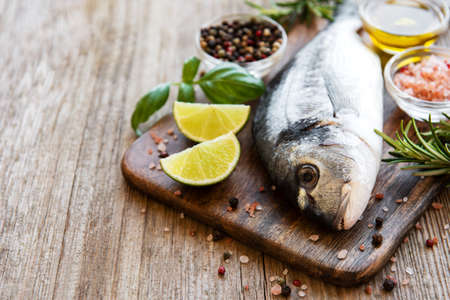 Fresh fish dorado. Dorado and ingredients for cooking on a table.