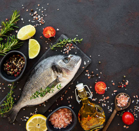 Fresh fish dorado. Dorado and ingredients for cooking on a table.の写真素材