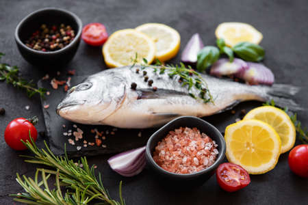 Fresh fish dorado. Dorado and ingredients for cooking on a table.の写真素材