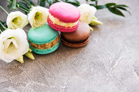 Colorful macaroons with flowers on a concrete background