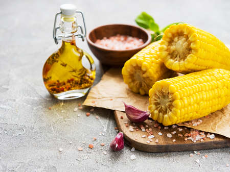 Boiled corn cobs, olive oil and salt on a concrete backgroundの写真素材