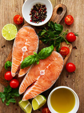 Raw salmon steaks and ingredients on a old wooden tableの写真素材