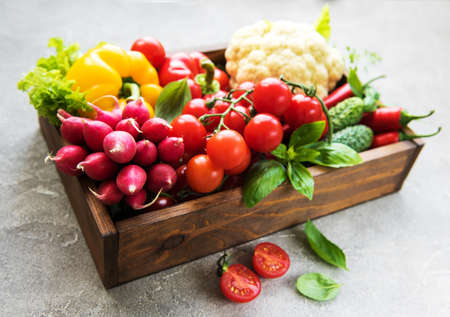 Box with  different raw vegetables on a old concrete backgroundの写真素材