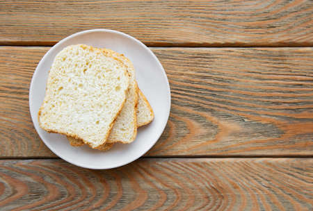 Slice of fresh wholemeal bread with plate on a wooden table