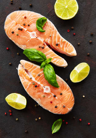 Raw salmon steaks and ingredients on a black slate boardの写真素材