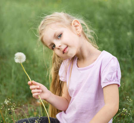 Little girl with dandelions on a fieldの写真素材