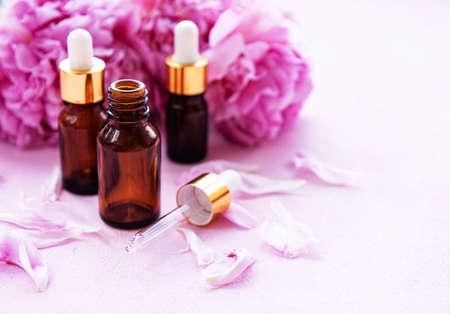 Aromatherapy essentials oils and pink peonies on a pink concrete backgroundの写真素材