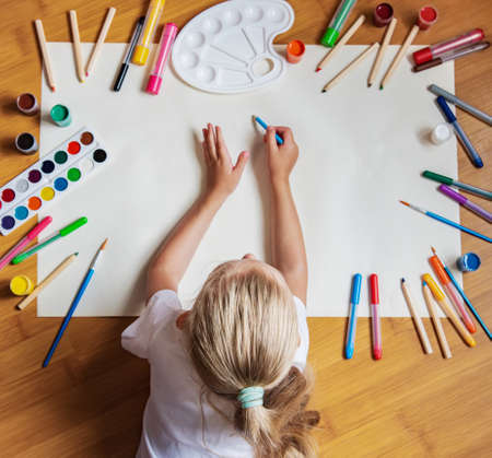 Little girl drawing with color pen in paper on floor  at home with copy spaceの写真素材