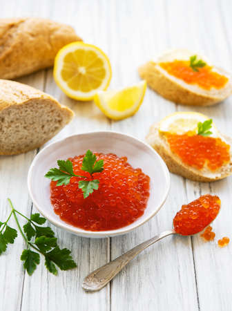 Red caviar in bowl and sandwiches on a old wooden tableの写真素材