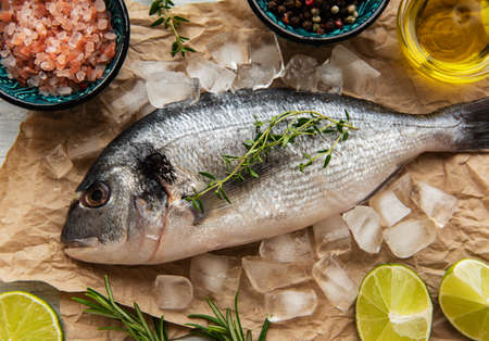 Fresh fish dorado. Dorado and ingredients for cooking on a table.の写真素材