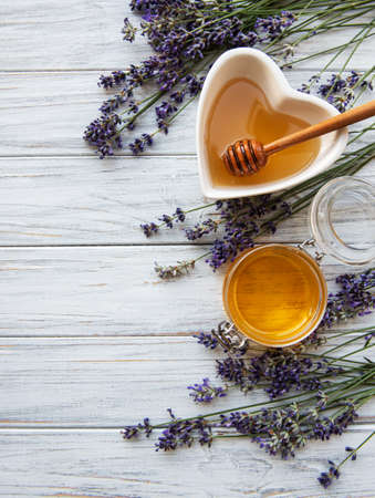 Bowl of liquid honey with lavender on white wooden table,  flat layの写真素材