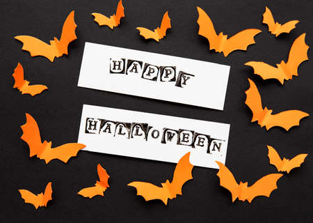 halloween  concept - orange paper bats flying over black background