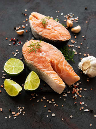 Raw salmon steaks and ingredients on a black slate board