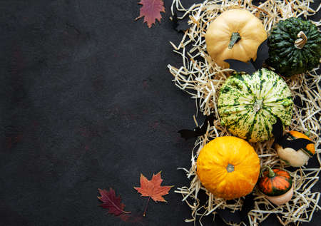 Pumpkins  on a black background with decorative bat and straw. Halloween concept, flat lay.の写真素材