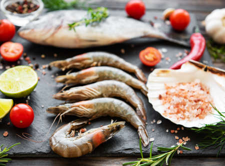 Fresh raw  prawns, dorado fish and spices on  black stone backgroundの写真素材
