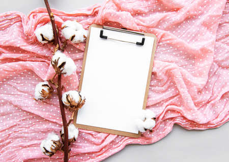 Stylized arranged office accessories clipboard,  cotton flowers, scarf. Women's fashion accessories  on white background. Flat lay Top viewの写真素材