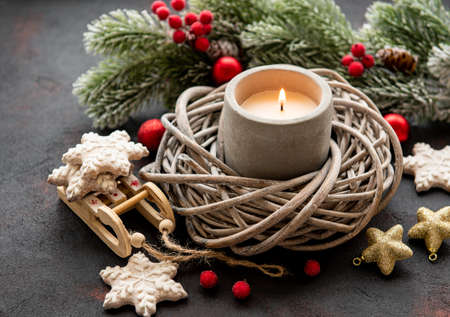Burning candle with Christmas decoration, fir tree, cookies,  baubles on black concrete backgroundの写真素材