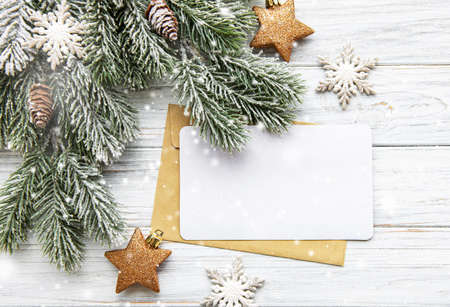Christmas tree branch with pine cones, greeting card and decorations on white wooden  background with copy space