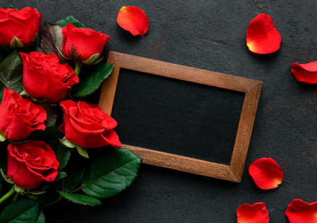 Valentines day romantic background - red roses, gift and blackboard on a black concrete background....