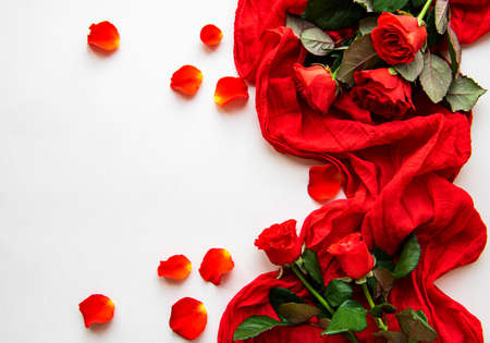 Red roses heads ans scarf scattered on a white background, overhead view. Flat layの写真素材