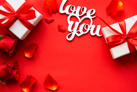 Valentines day romantic background - red roses, gift and hearts on a red background. Flat lay, copy...