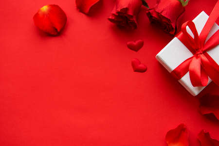 Valentines day romantic background - red roses, gift and hearts on a red background. Flat lay, copy space.の写真素材