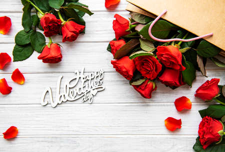 Frame made of red roses, petals   on white wooden background. Flat lay, top view, copy space.の写真素材