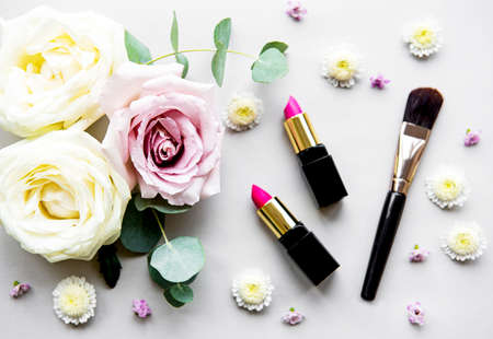 Decorative flat lay composition with cosmetics and flowers. Top view on white backgroundの写真素材