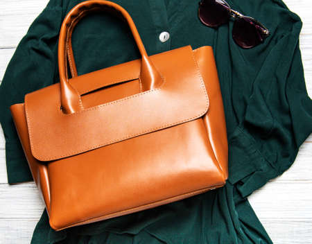 Brown leather women's bag and green blouse. Women's spring or summer outfit. Apparels flat layの写真素材