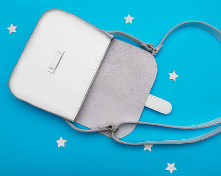 White woman leather hand bag with long handle on blue background. Flat lay