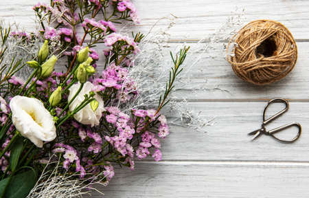 Florist workplace: flowers and accessories on a whitw wooden table. Flat lay. 